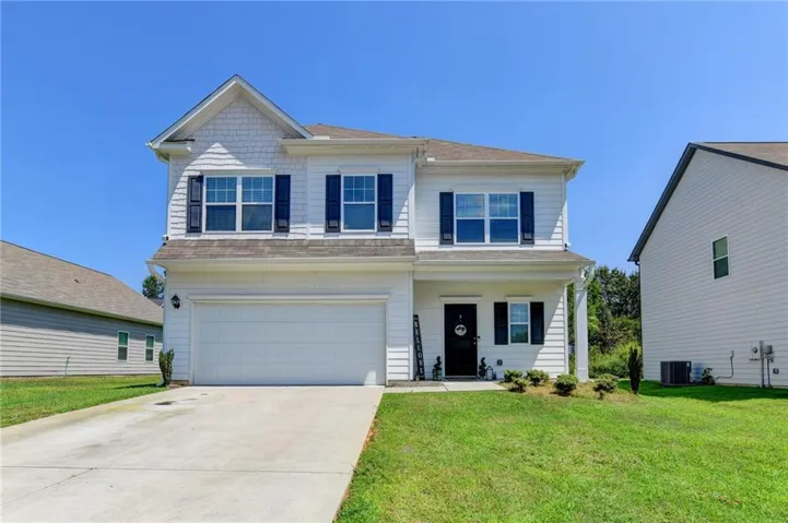 Two-story residence featuring white siding, a two-car garage, and a covered entry