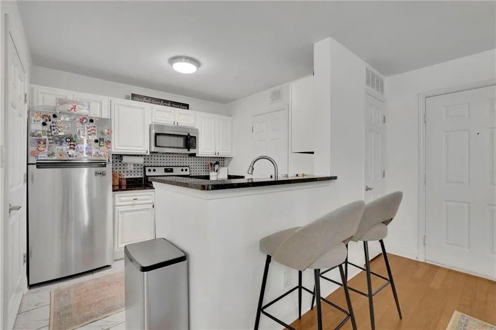 Kitchen featuring appliances with stainless steel finishes, light hardwood / wood-style flooring, white cabinets, and kitchen peninsula