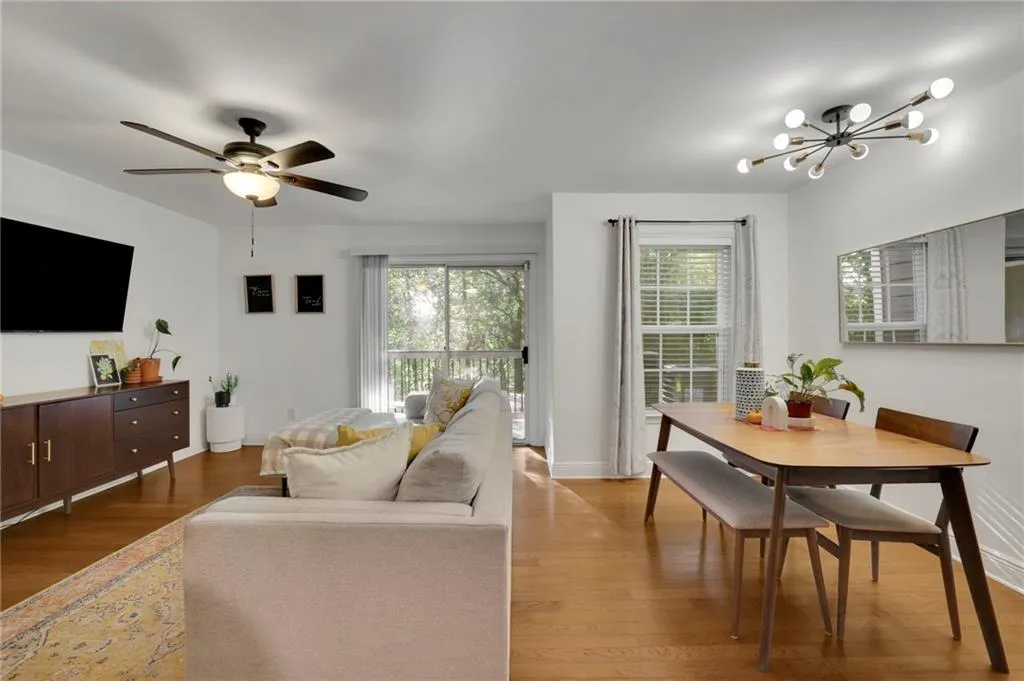 Living room featuring a healthy amount of sunlight, wood-type flooring, and ceiling fan with notable chandelier