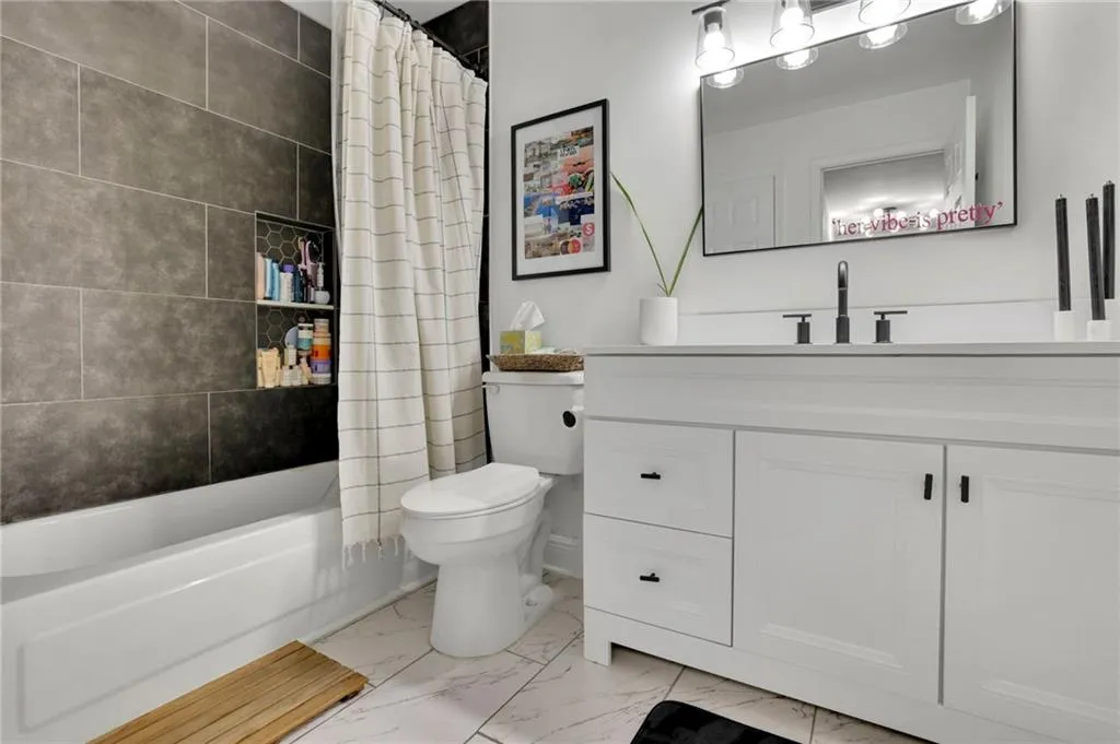 Full bathroom featuring vanity, toilet, and shower / bathtub combination with curtain