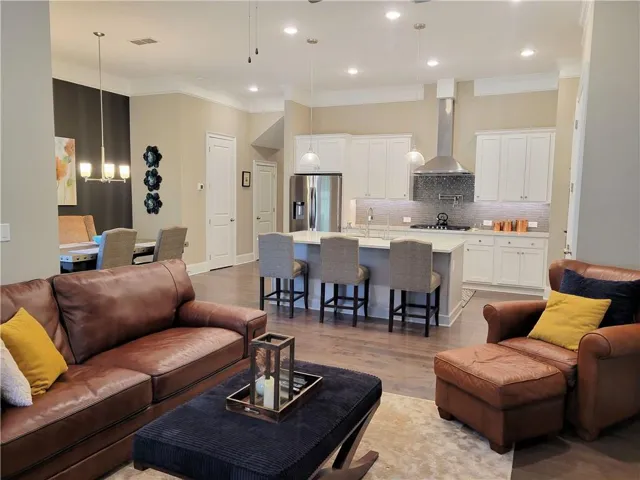 Open-concept living space featuring wood-finish flooring, recessed lighting, and crown molding