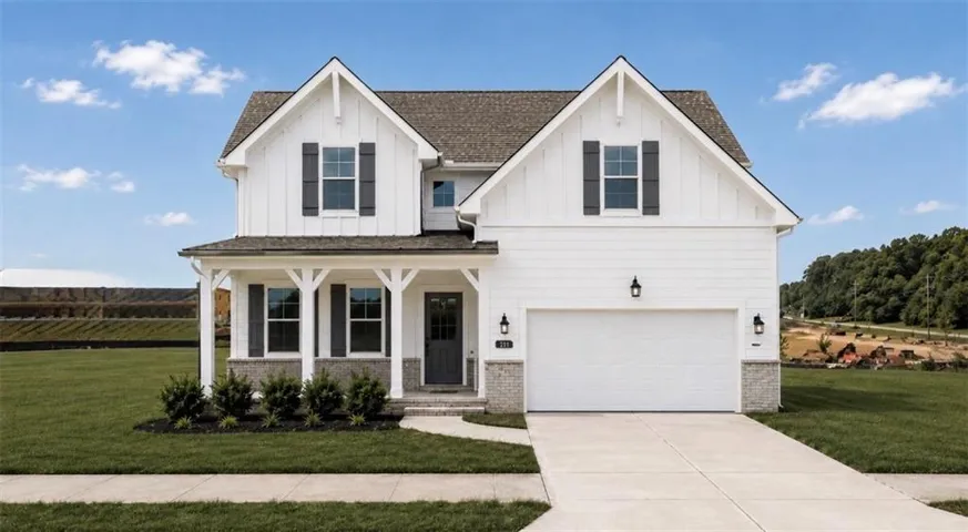 Modern farmhouse exterior featuring white vertical and horizontal siding, a covered front porch with white columns, a two-car garage, and stone accents