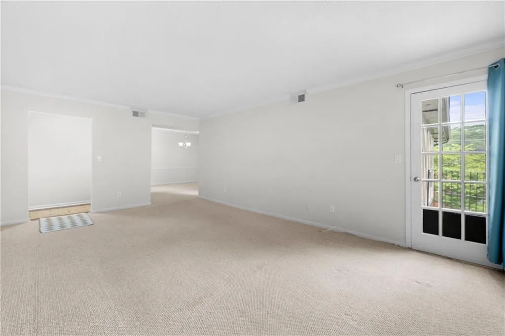Spare room with carpet flooring, ornamental molding, and an inviting chandelier