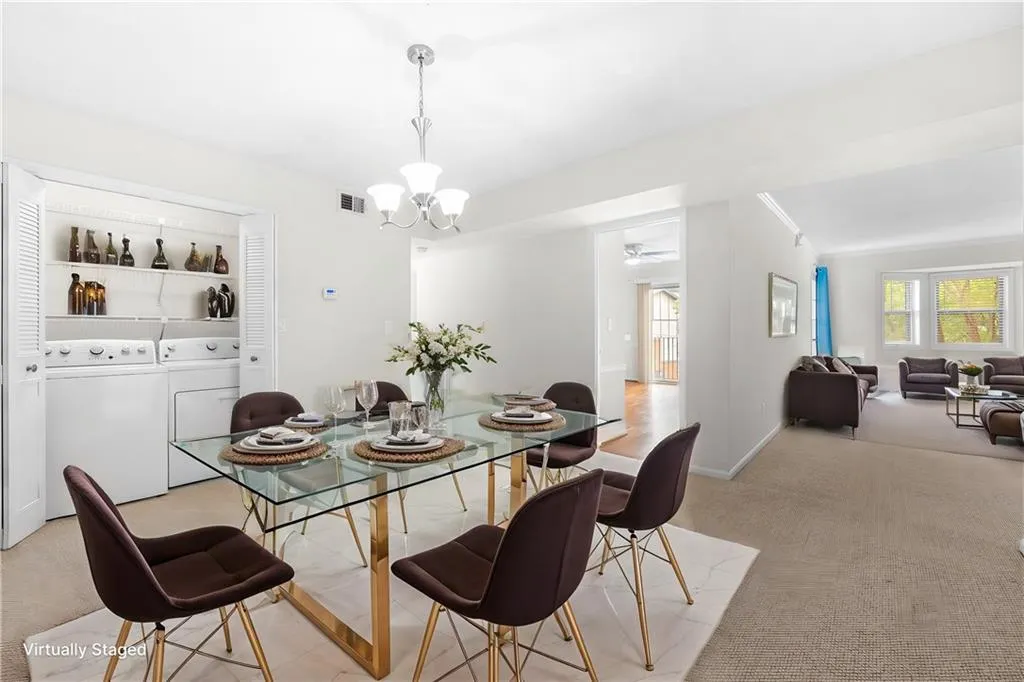 Carpeted dining area featuring built in shelves, ceiling fan with notable chandelier, washer and clothes dryer, and a healthy amount of sunlight