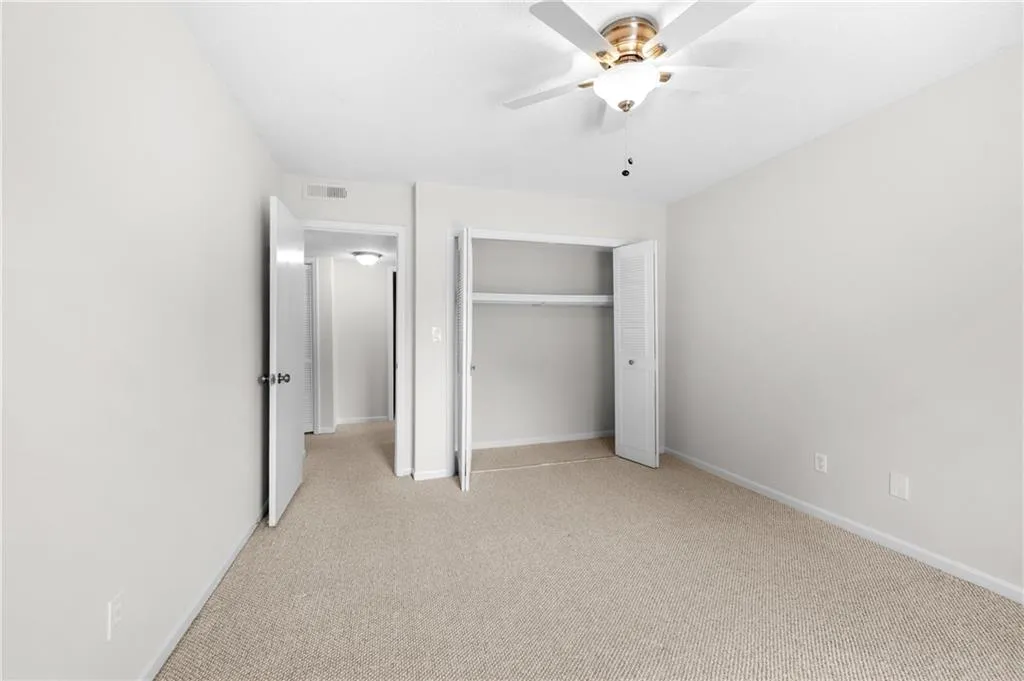 Unfurnished bedroom with ceiling fan, a closet, and light colored carpet
