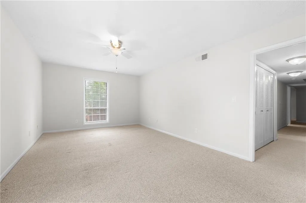 Carpeted empty room featuring ceiling fan