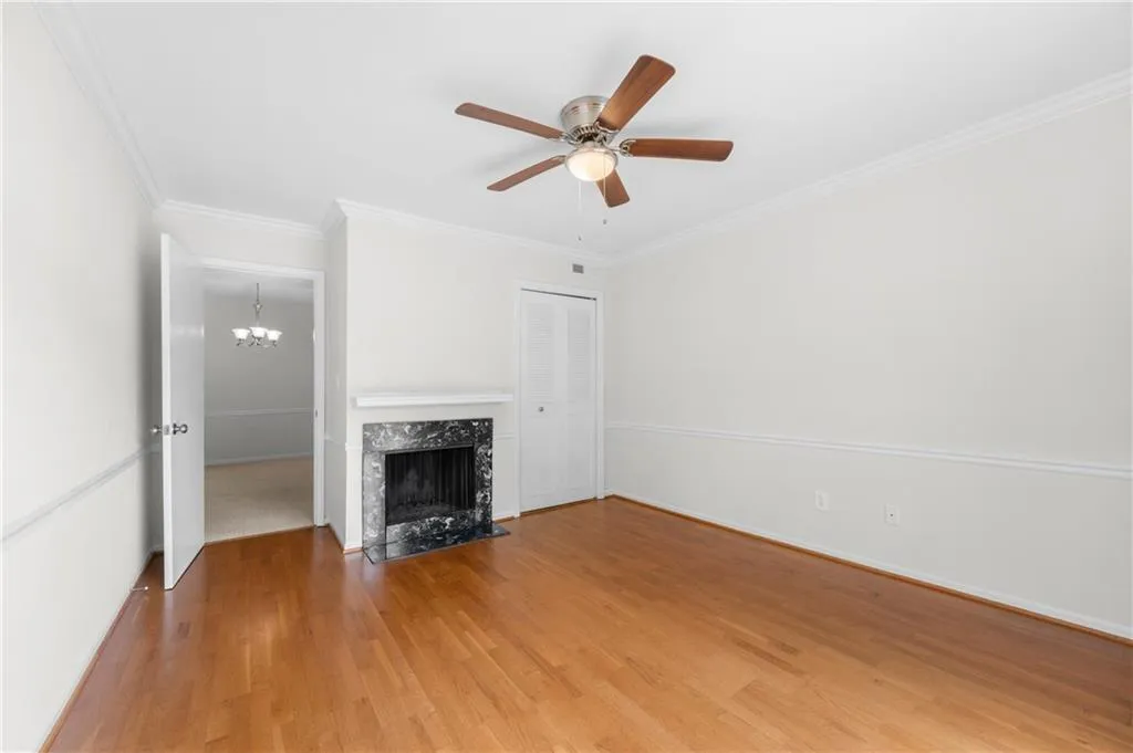 Unfurnished living room featuring hardwood / wood-style floors, a high end fireplace, ceiling fan with notable chandelier, and ornamental molding