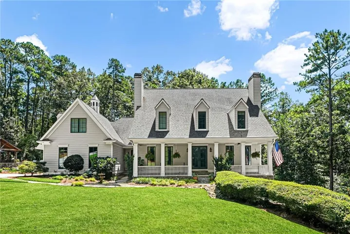 Two-story residence featuring light gray siding, a covered front porch with white columns, dormer windows, and a cupola