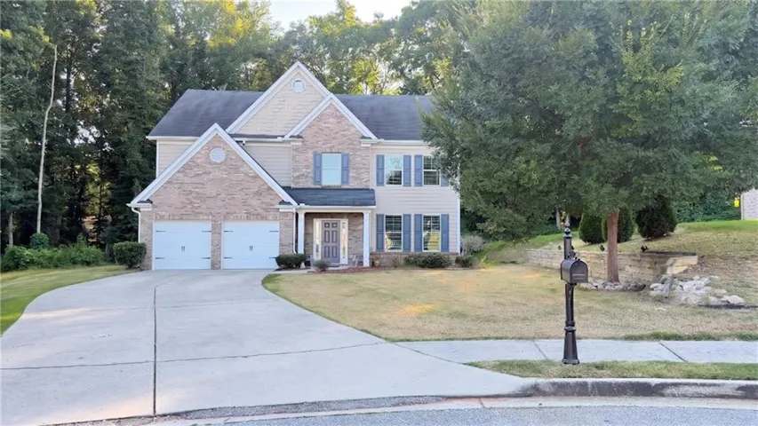 Two-story residence featuring a brick and siding facade, an attached two-car garage, and a concrete driveway