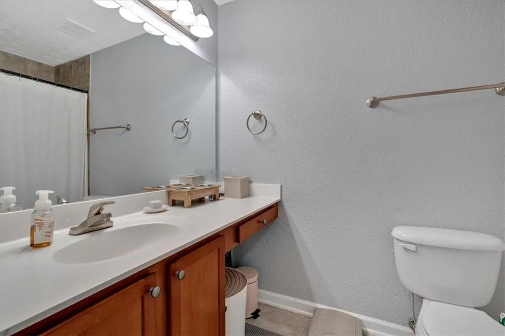 Attached Bathroom with oversized vanity, toilet, and tile patterned floors