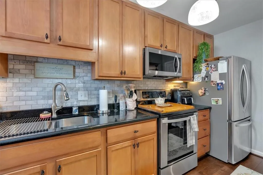 Kitchen featuring appliances with stainless steel finishes, sink, dark hardwood / wood-style floors, and tasteful backsplash
