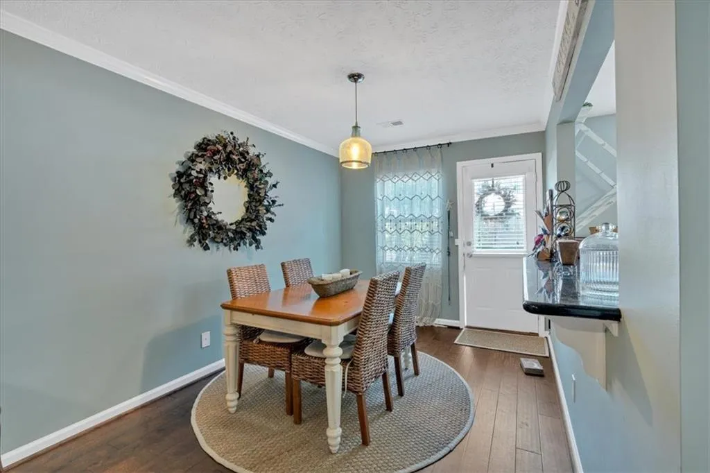 Dining area with crown molding, dark wood-type flooring.