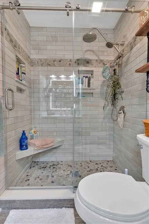 Bathroom featuring toilet and an custom walk-in shower with custom upgraded tiles and features.