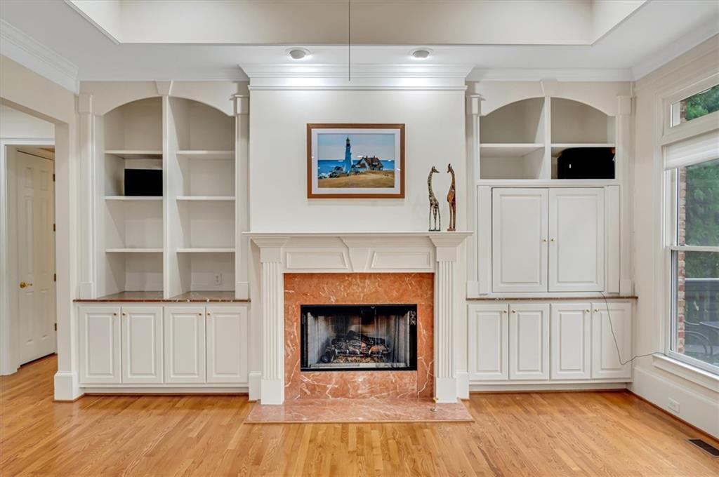 Unfurnished living room with a premium fireplace, light hardwood / wood-style floors, crown molding, and built in features