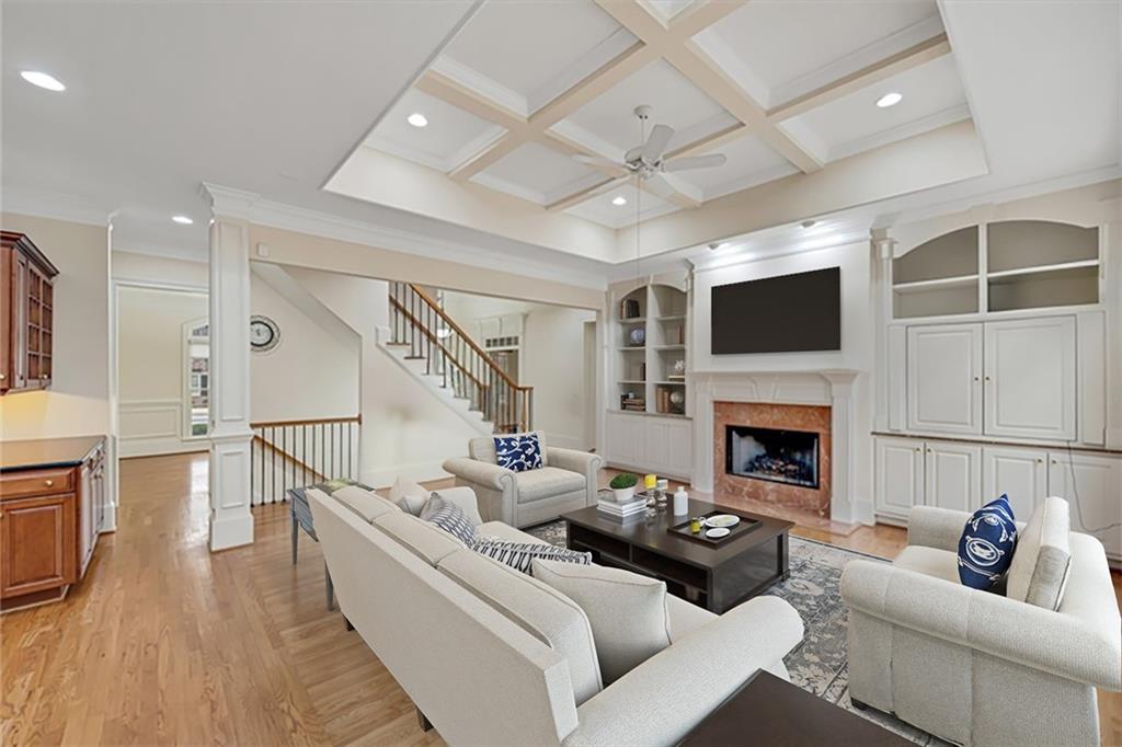 Living room featuring a premium fireplace, coffered ceiling, beam ceiling, light wood-type flooring, and ceiling fan