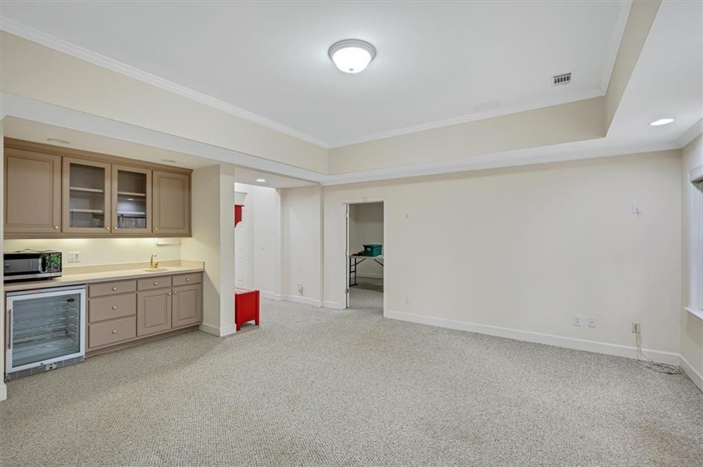 Kitchen featuring wine cooler, light carpet, ornamental molding, and sink