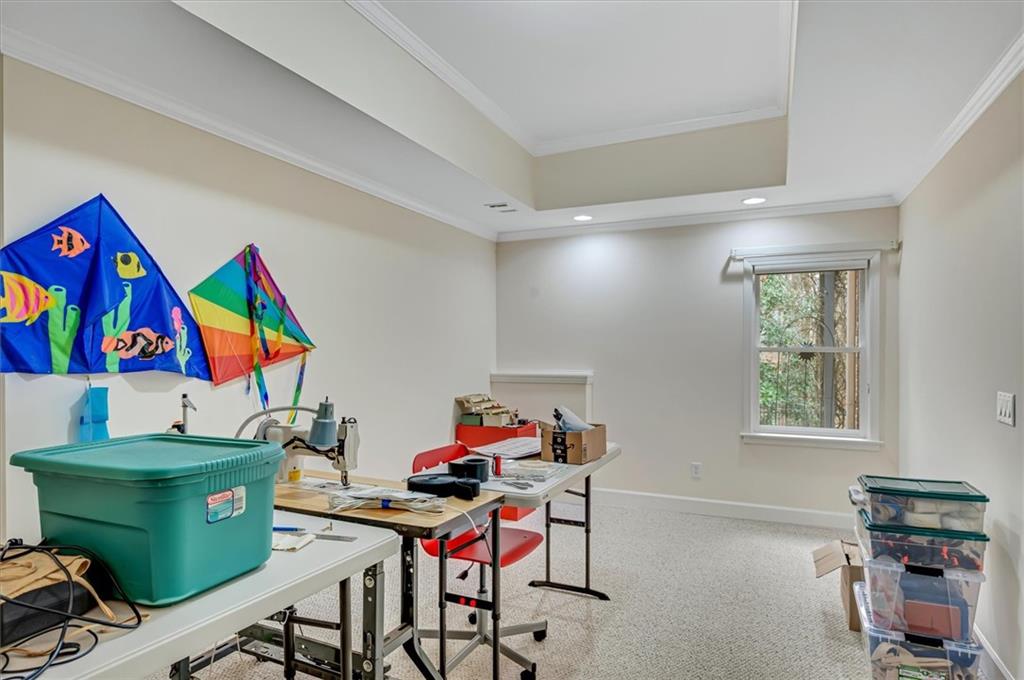 Carpeted office space with a tray ceiling and ornamental molding