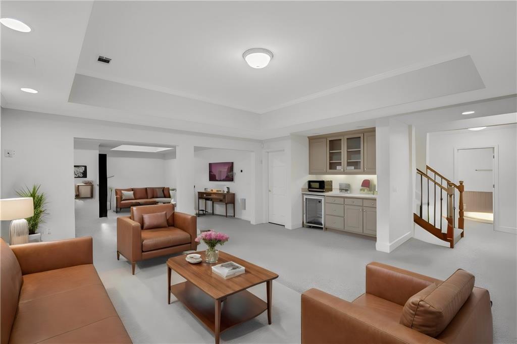 Living room featuring wine cooler, a raised ceiling, and light carpet