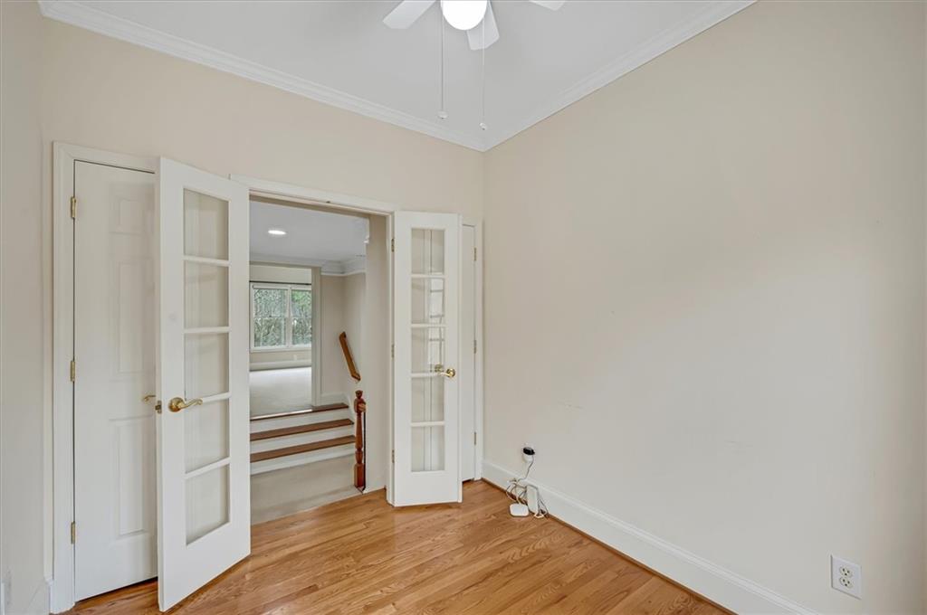 Empty room featuring light hardwood / wood-style flooring, crown molding, ceiling fan, and french doors