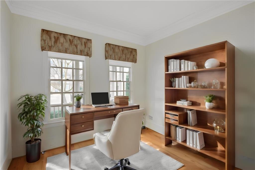 Office area with light hardwood / wood-style floors and crown molding