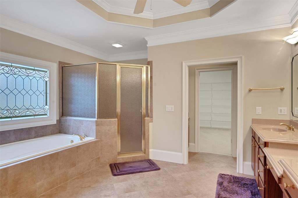 Bathroom featuring plus walk in shower, tile floors, oversized vanity, and ornamental molding