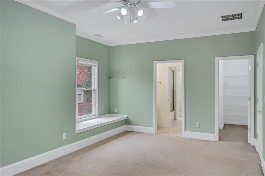 Unfurnished bedroom featuring light carpet, a spacious closet, ceiling fan, and a closet