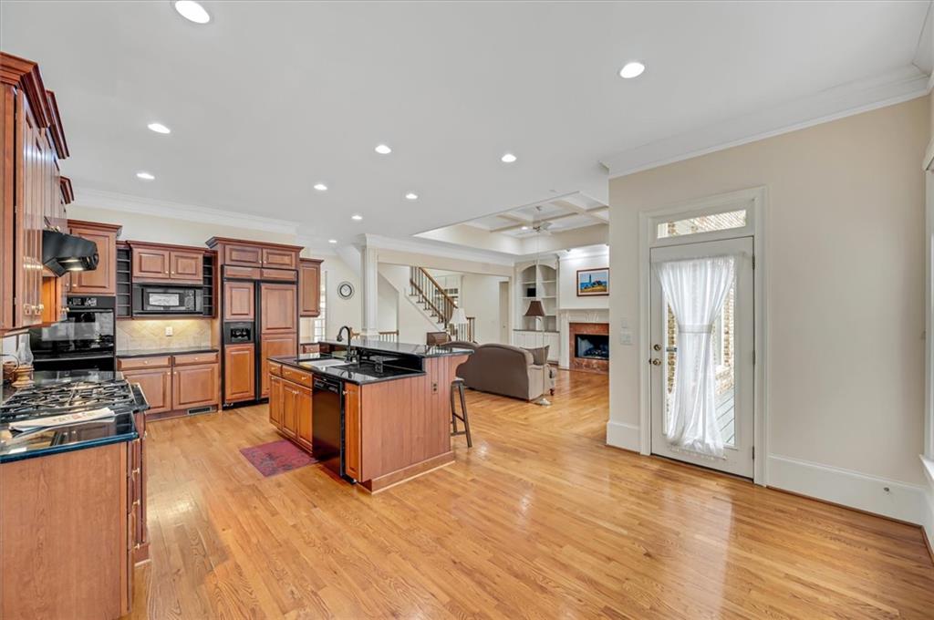Kitchen with a kitchen island with sink, light wood-type flooring, tasteful backsplash, a breakfast bar, and built in appliances