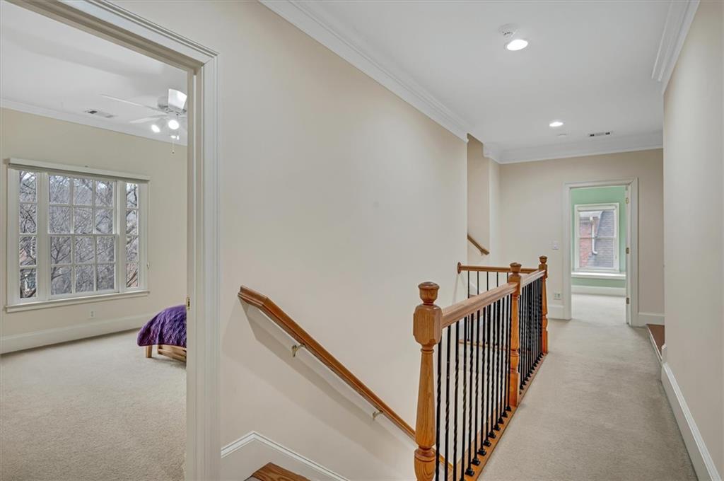 Hallway with crown molding and light carpet