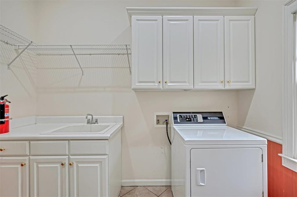 Laundry area with cabinets, sink, light tile floors, and washer / clothes dryer