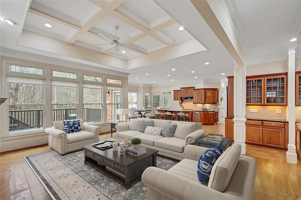 Living room with ceiling fan, crown molding, beam ceiling, coffered ceiling, and ornate columns