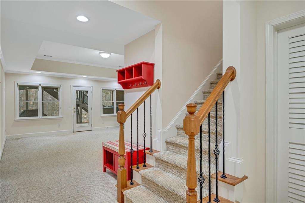 Stairway featuring light carpet and a raised ceiling
