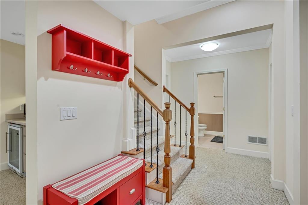 Stairs featuring wine cooler, light carpet, and ornamental molding