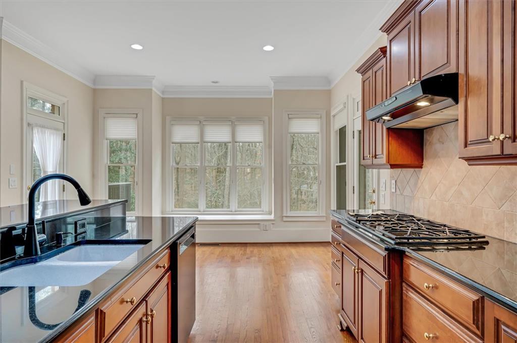 Kitchen with backsplash, light hardwood / wood-style floors, appliances with stainless steel finishes, crown molding, and sink
