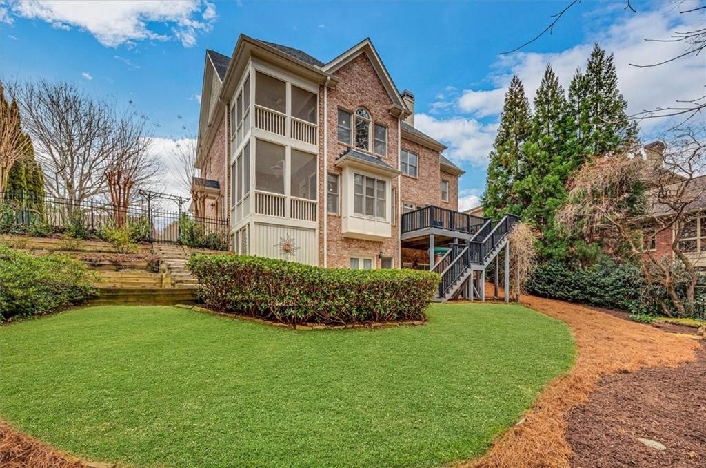 Back of house featuring a lawn and a deck