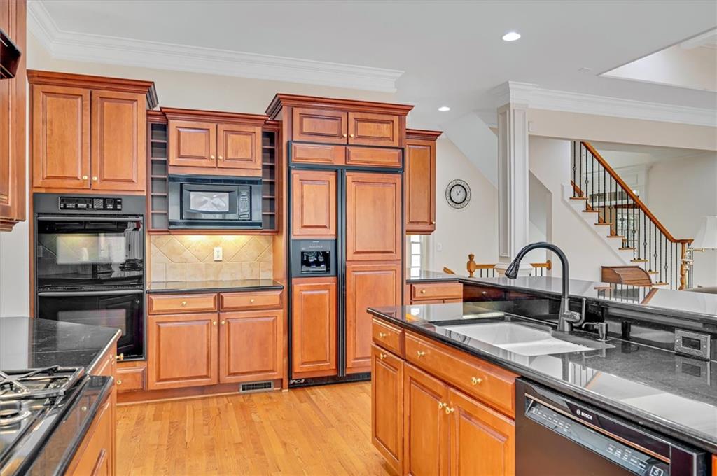 Kitchen with ornamental molding, backsplash, light hardwood / wood-style floors, sink, and black appliances
