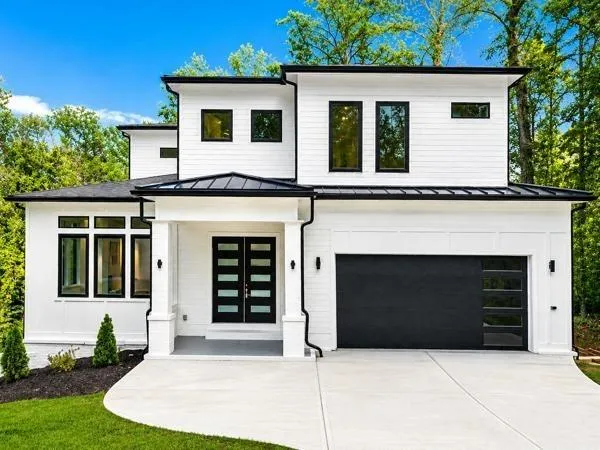 Modern white exterior with black trim, a prominent entry with double doors, and a black garage door with integrated windows
