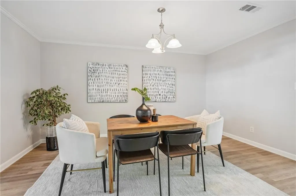 Dining area with a notable chandelier, crown molding, and light wood-type flooring
