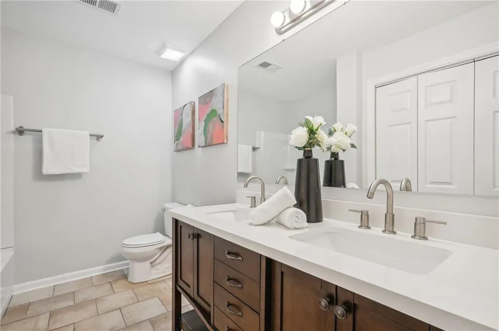 Bathroom featuring tile flooring, double sink vanity, and toilet