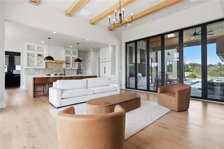 Expansive living space featuring wood-finish flooring, exposed beam ceiling and a 16x10 accordion glass door.