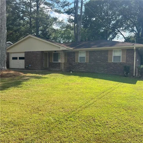 Ranch-style home with brick siding, a front yard, and a garage
