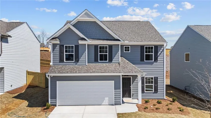 Two-story residence featuring a gray exterior, attached garage, and a covered entryway