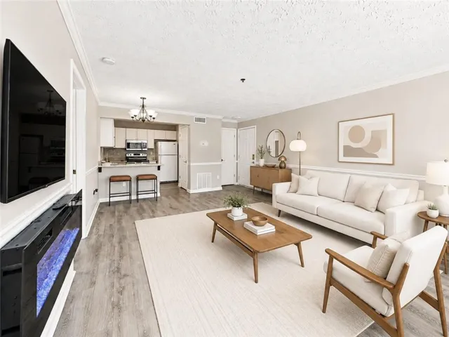 Open-concept living area with wood-finish flooring, a built-in electric fireplace, and crown molding