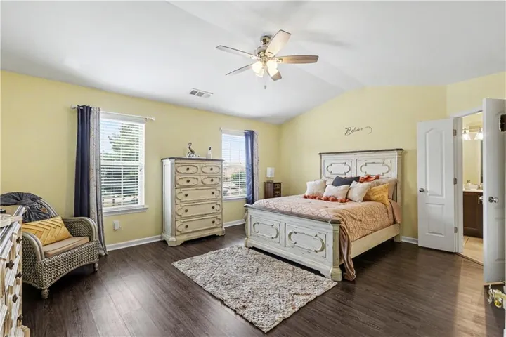 Primary Spacious room featuring vaulted ceilings, dark wood-finish flooring, and multiple windows with blinds