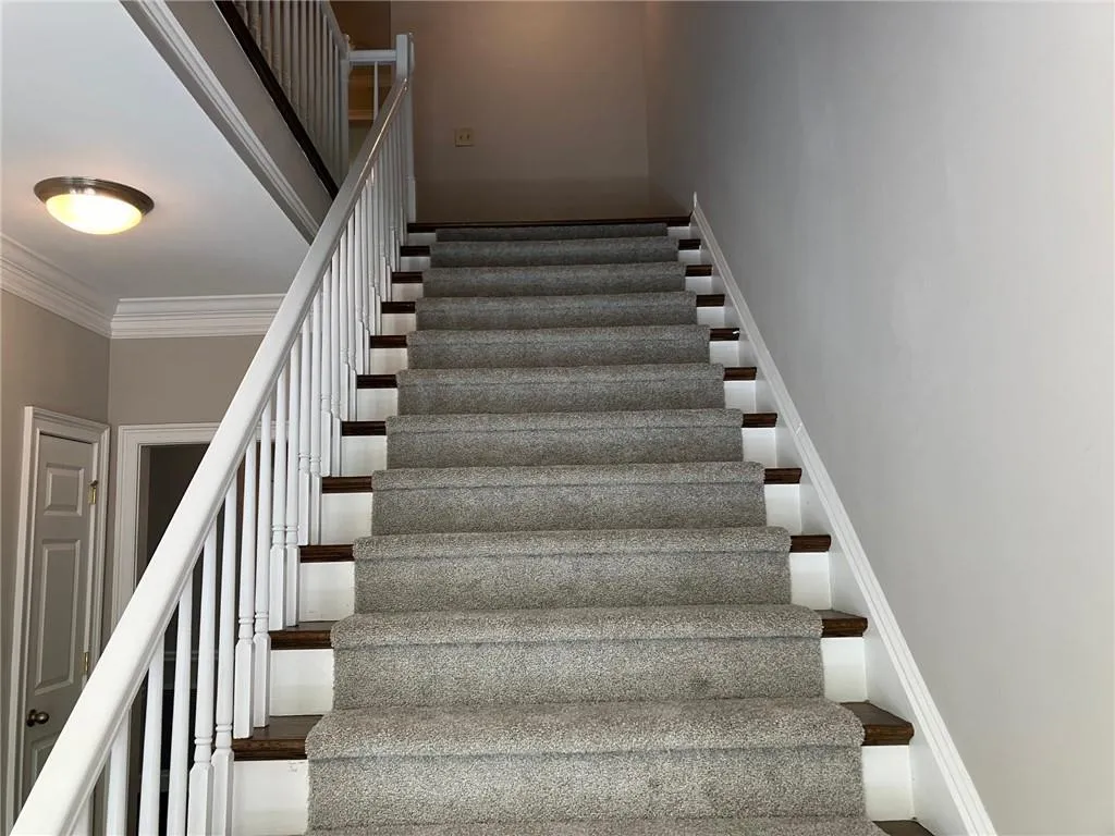Stairs featuring a high ceiling and crown molding