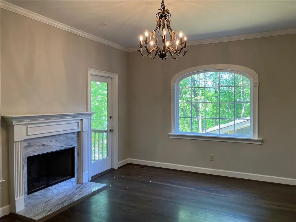 Unfurnished living room featuring a fireplace, a wealth of natural light, dark hardwood / wood-style flooring, and an inviting chandelier