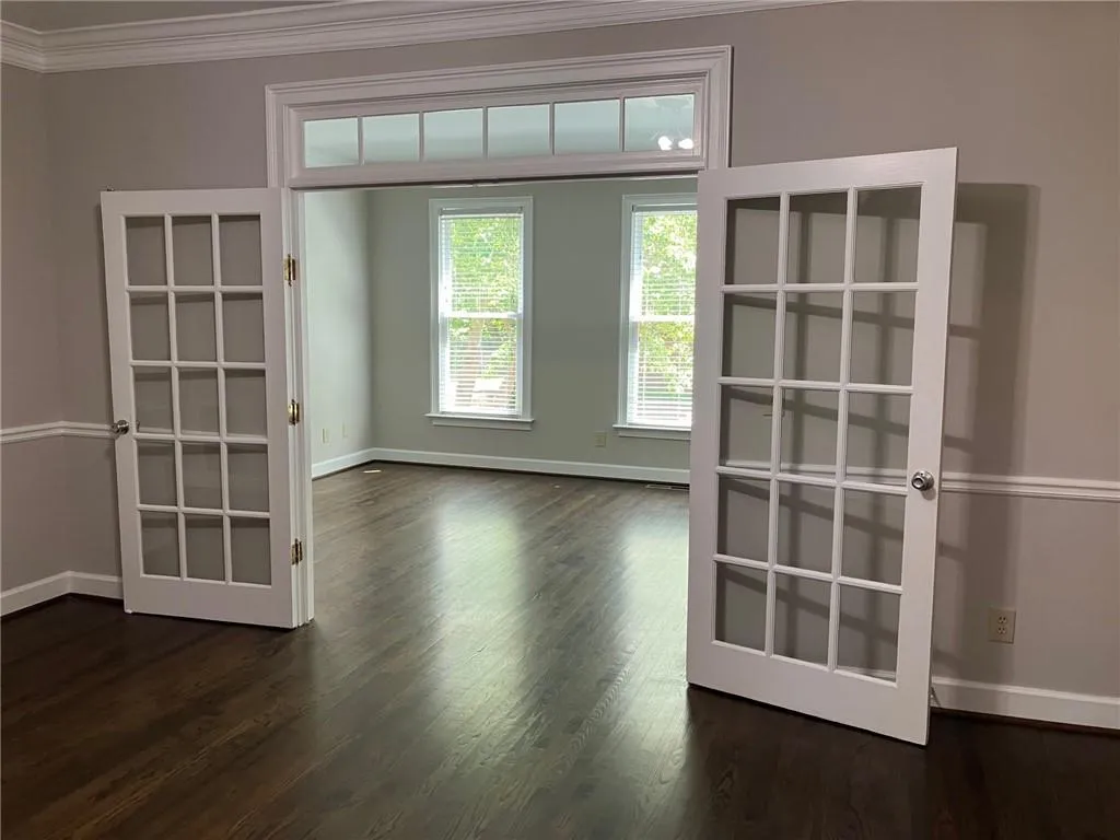 Empty room featuring ornamental molding, french doors, and dark wood-type flooring