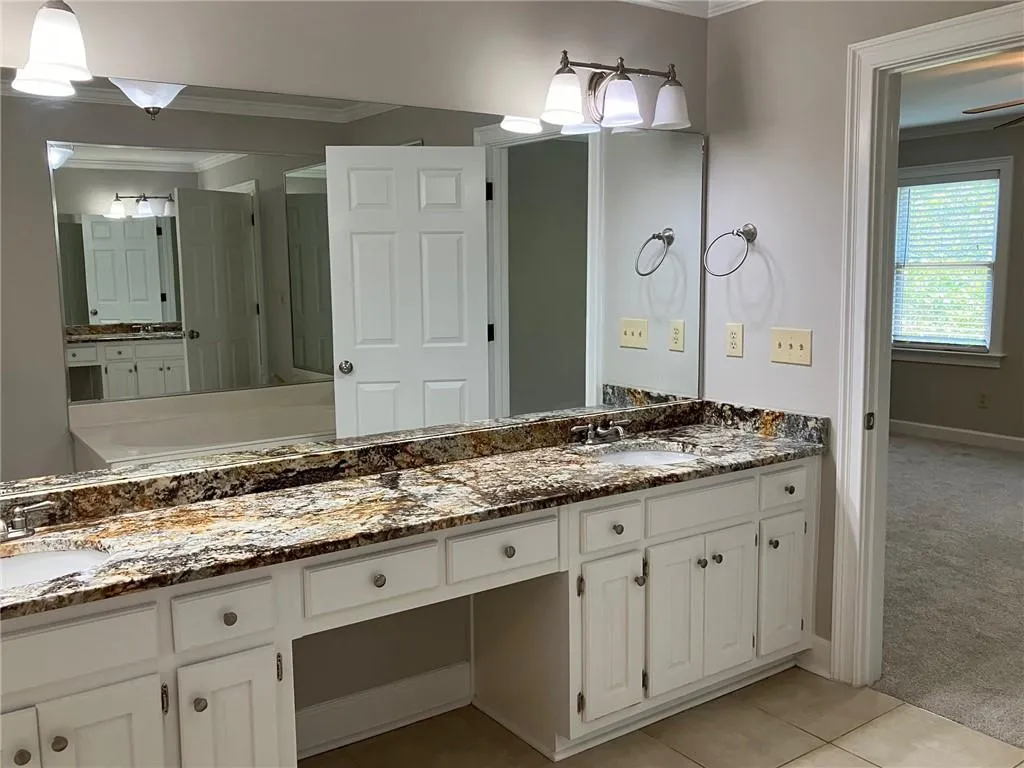 Bathroom featuring ornamental molding, dual bowl vanity, and tile flooring