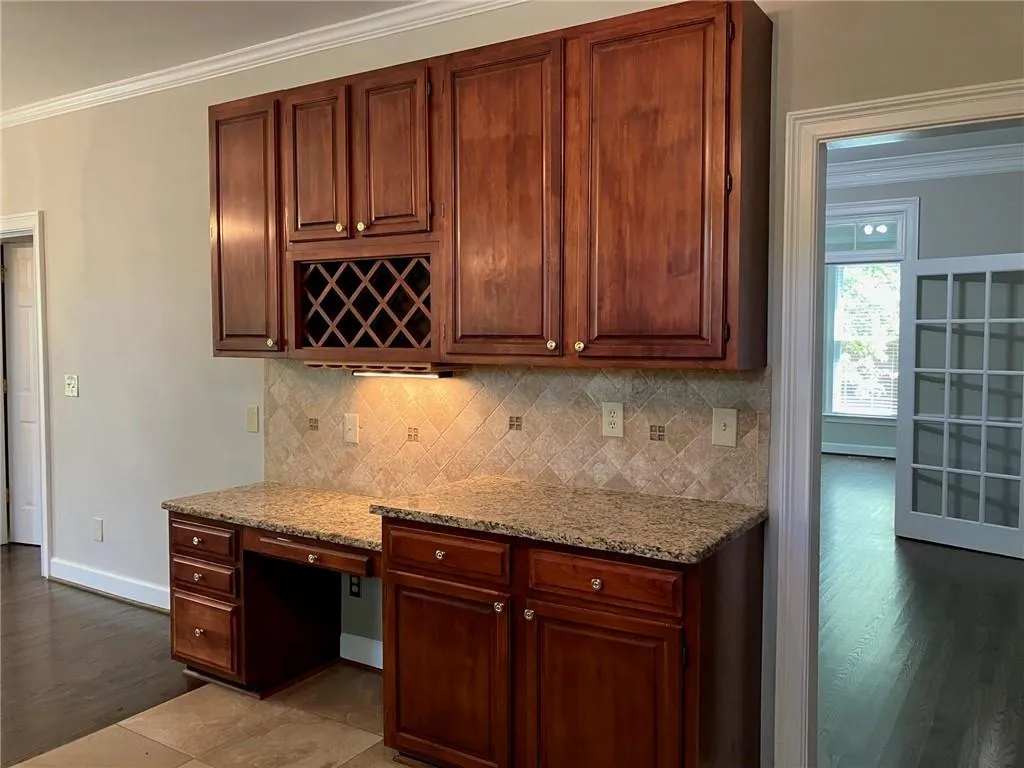 Kitchen with hardwood / wood-style floors, ornamental molding, tasteful backsplash, and light stone countertops