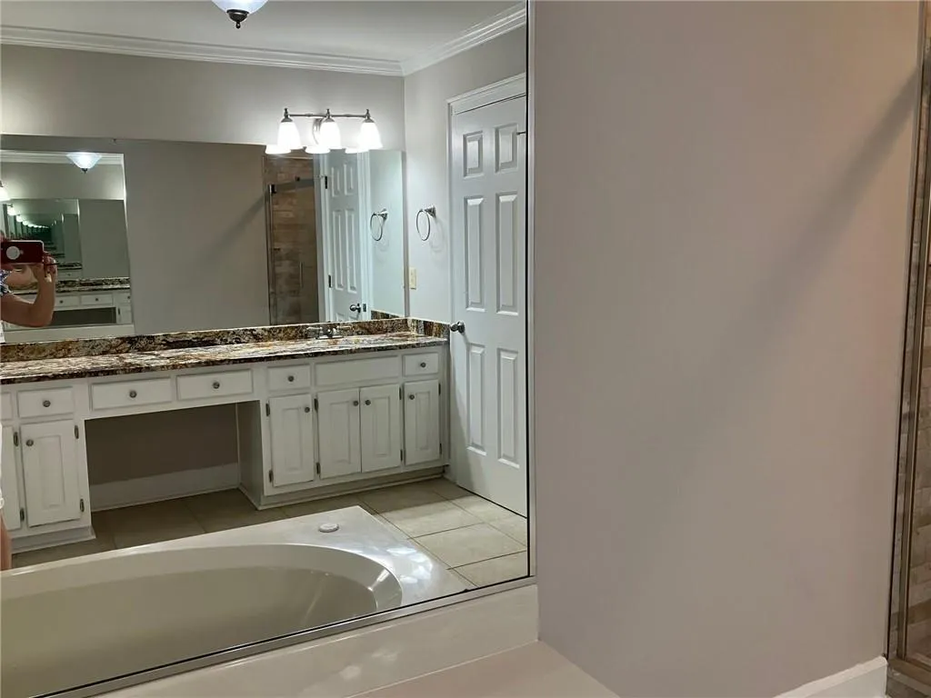 Bathroom featuring a bath, vanity, and crown molding