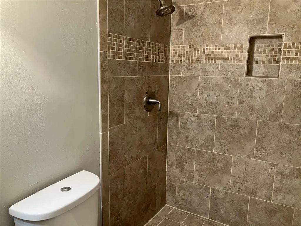 Bathroom featuring tiled shower and toilet